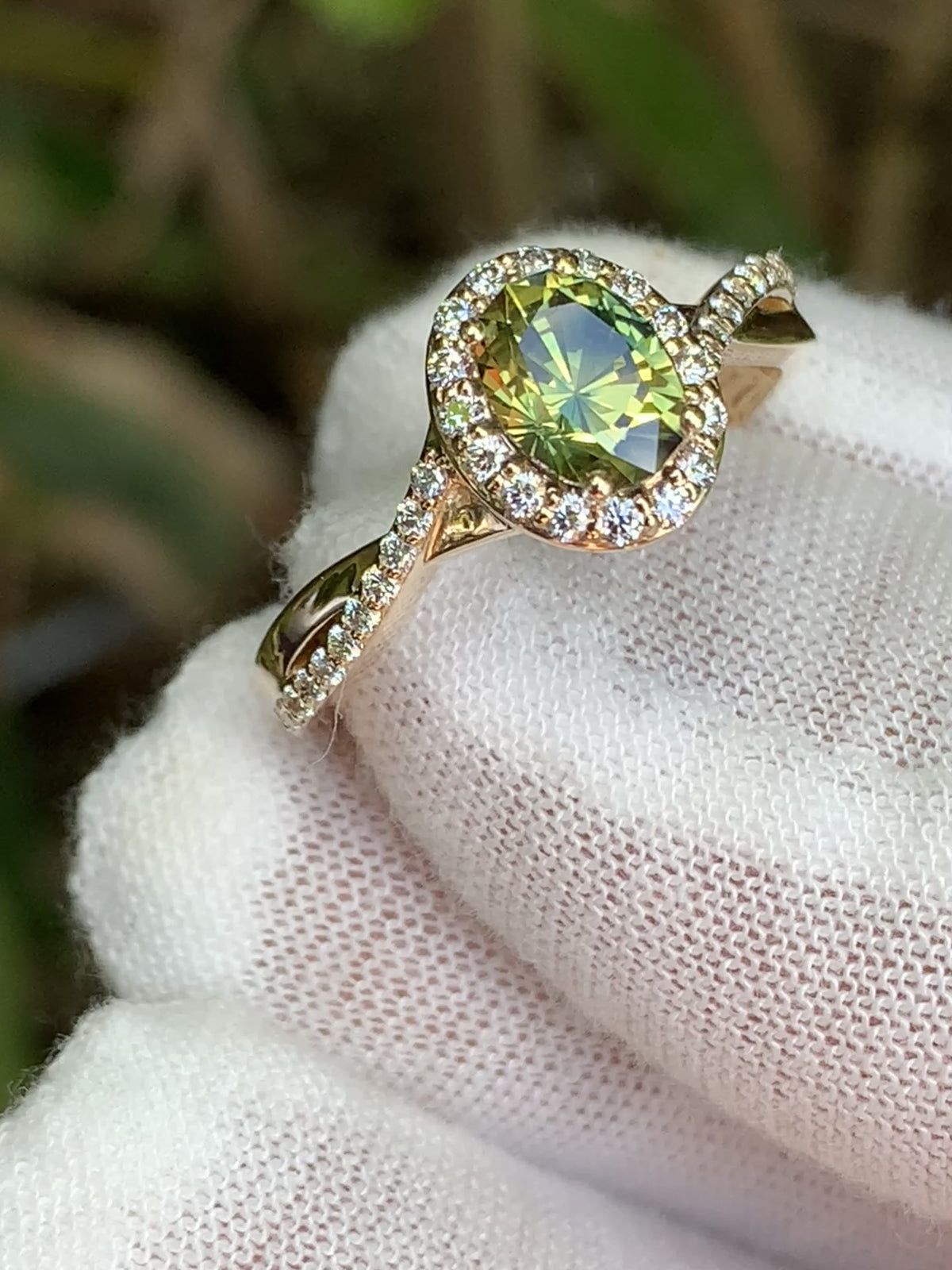 Oval yellow-green sapphire surrounded by white accent stones, with a twisting band.
